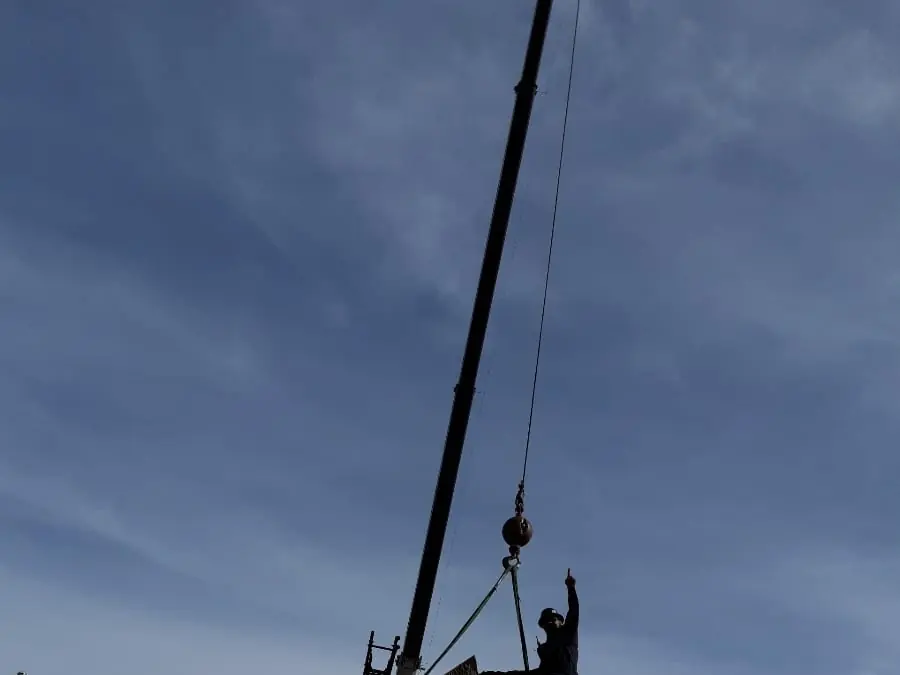 Crane boom and rigger in silhouette against the sky